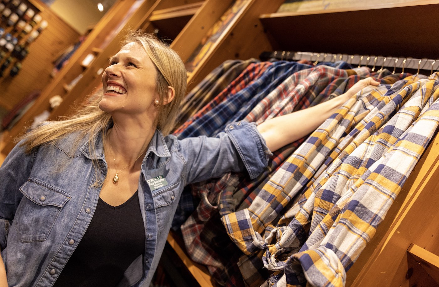 Female Orvis Employee helping customers with shirts